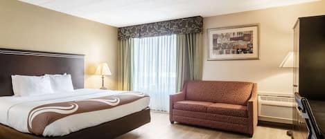 A hotel room with a large bed, a sofa, a television, and a window with curtains.