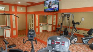 A gym with cardio equipment, weight machines, and a television displaying a news program. - Quality Inn & Suites Indiana South (Indiana)