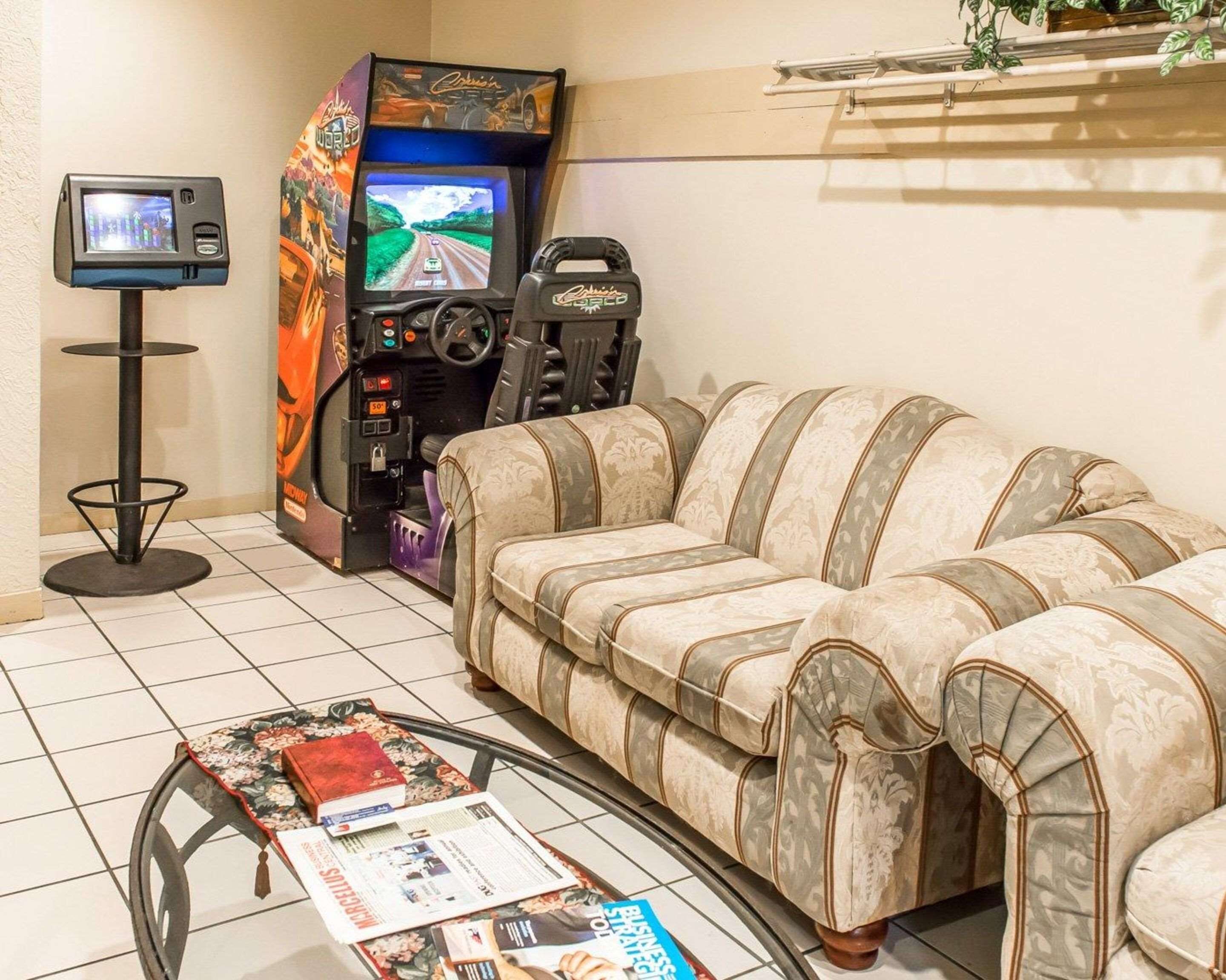 A gaming area with a sofa, a small table with magazines, and two arcade machines.