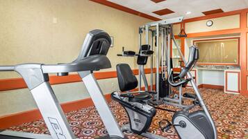 A gym with cardio machines, weightlifting equipment, and a patterned carpet.