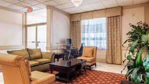 A hotel room with a sofa, armchair, desk, and a large plant. - Quality Inn & Suites Indiana South (Indiana)
