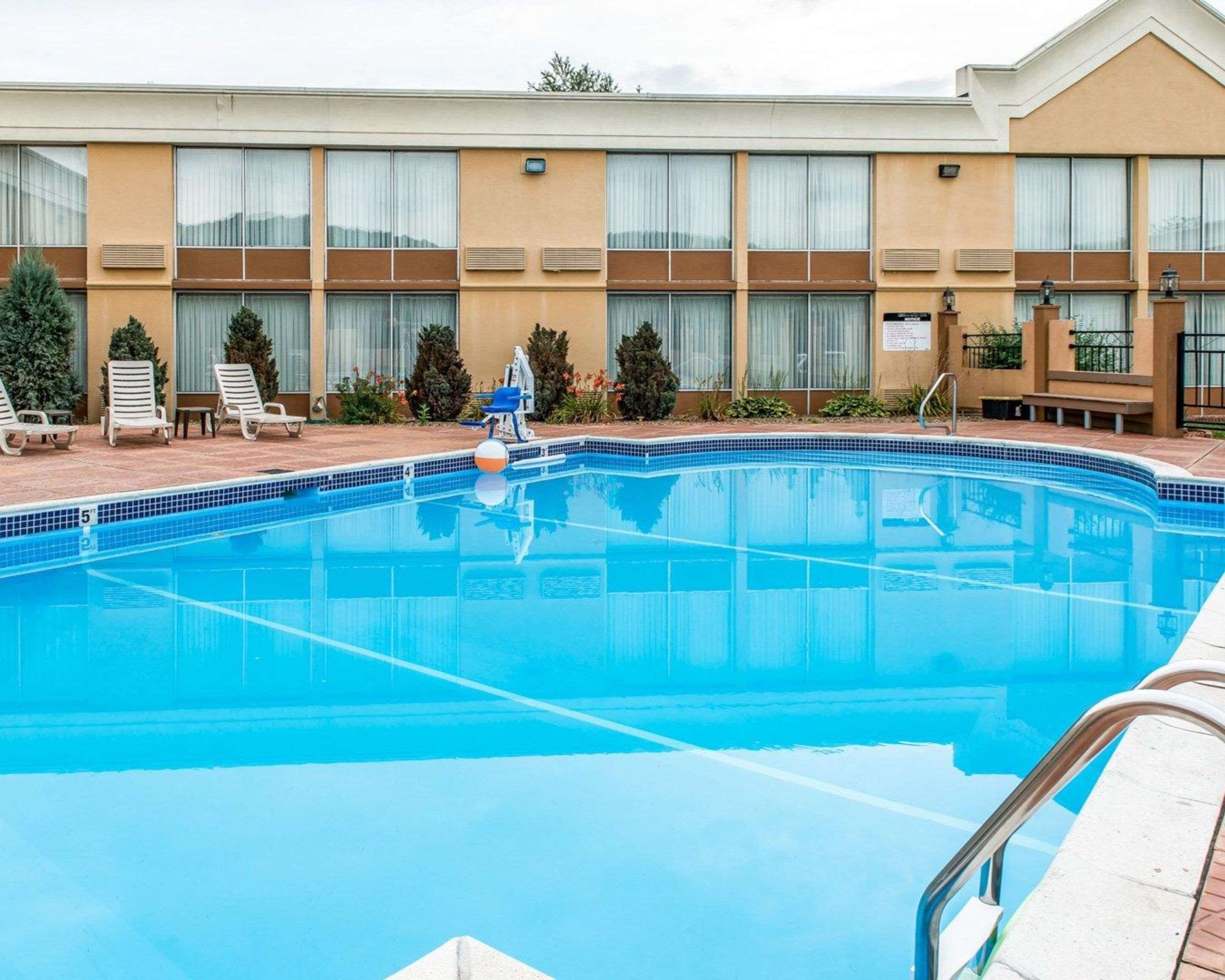 A swimming pool with lounge chairs and a building with large windows in the background.