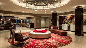 A modern lobby with a circular seating area, a reception desk, and a large abstract wall mural. - DoubleTree by Hilton Hotel Largo/Washington DC (Upper Marlboro)