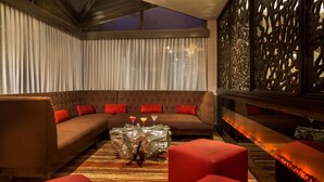 A modern lounge area with a sofa set, red cushions, a glass coffee table, and a decorative wall panel. - DoubleTree by Hilton Hotel Largo/Washington DC (Upper Marlboro)