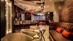 A modern lounge area with a sofa, chairs, a bar, and a wall with a unique pattern. - DoubleTree by Hilton Hotel Largo/Washington DC (Upper Marlboro)