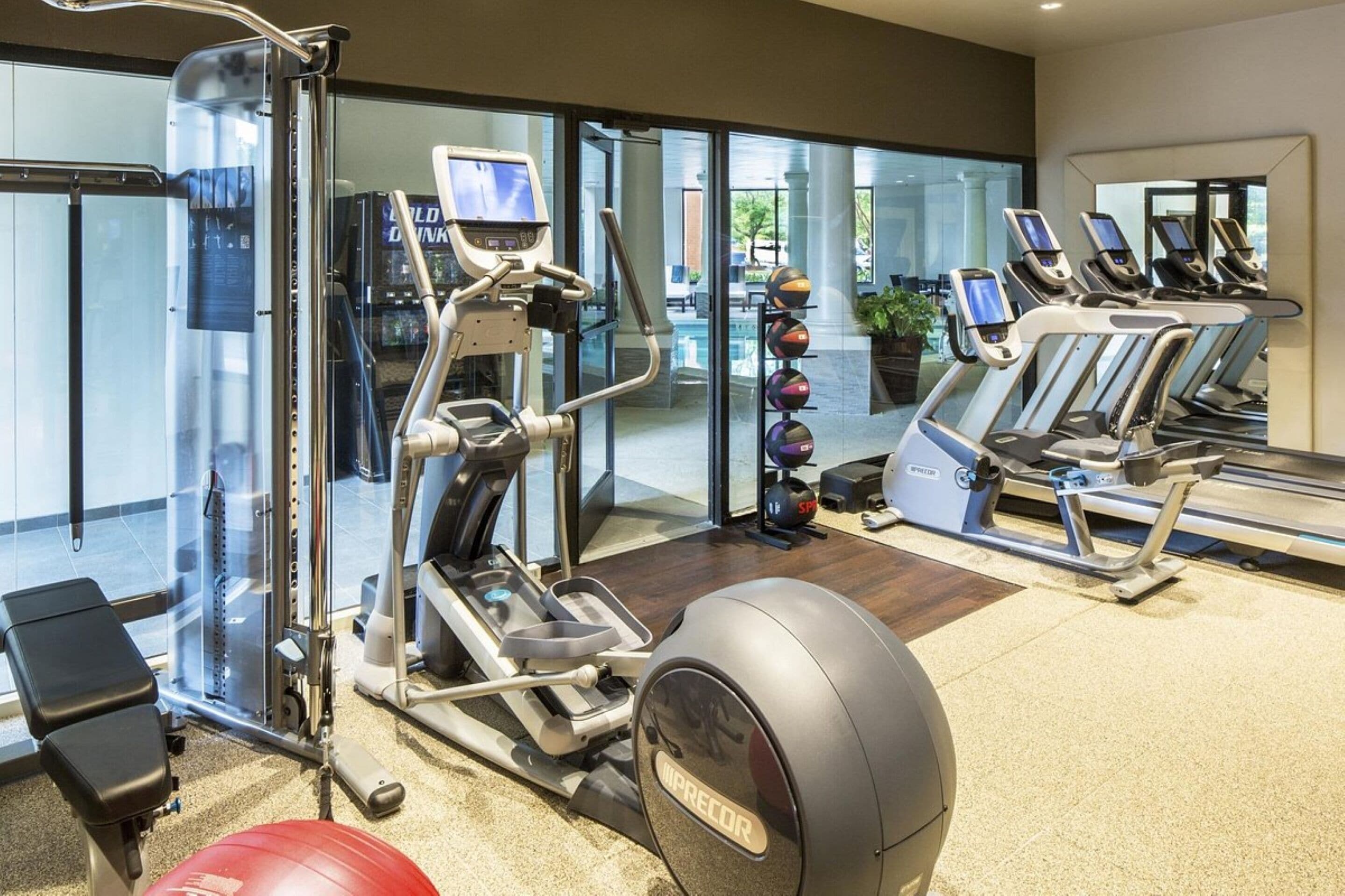 A gym with cardio machines, weight equipment, and a red exercise ball.