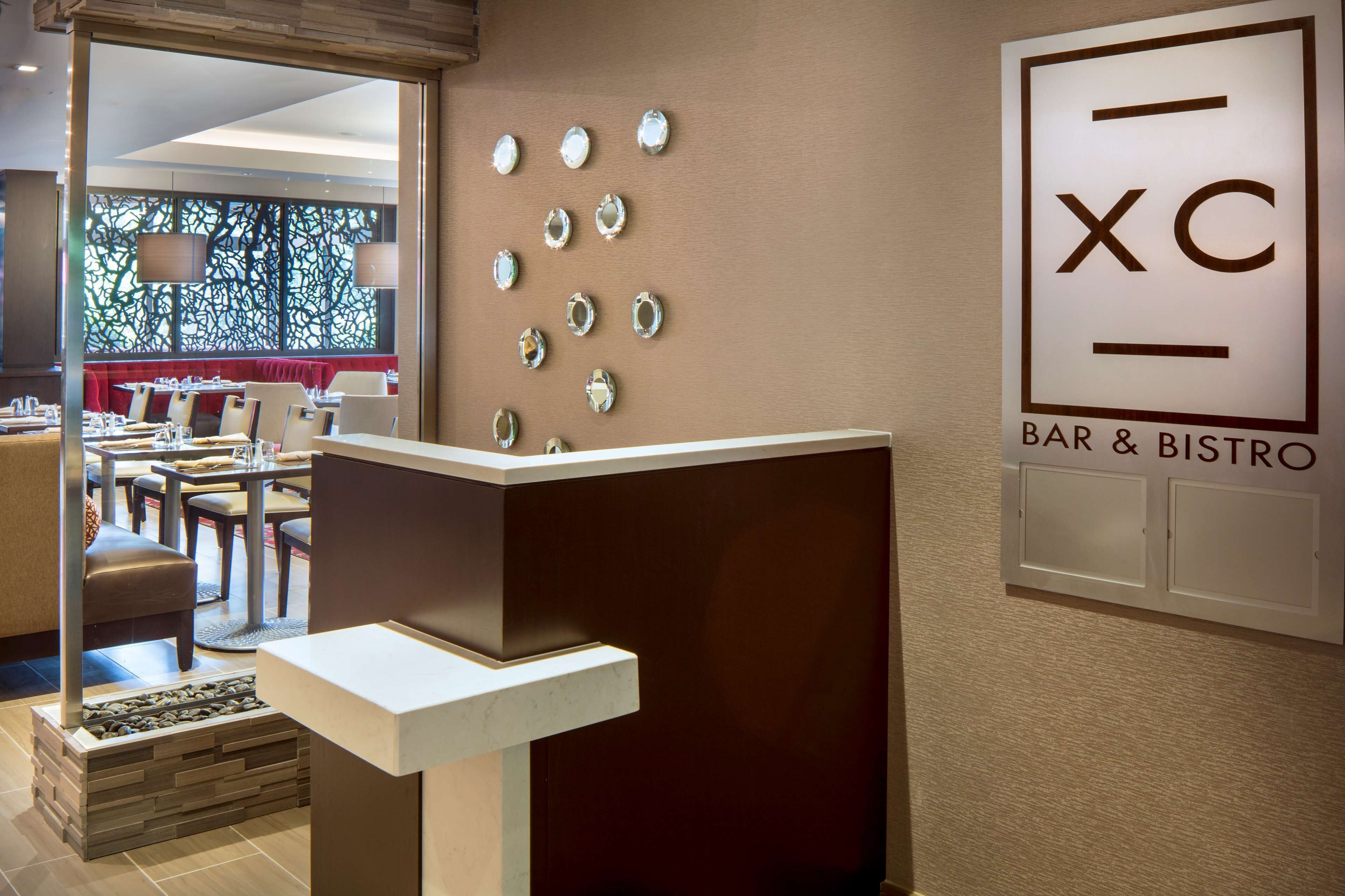 Een bar en bistro met een receptiebalie, zitplaatsen en decoratieve wandelementen.