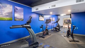 Un gimnasio con cintas de correr, bicicletas estáticas y una máquina de remo.