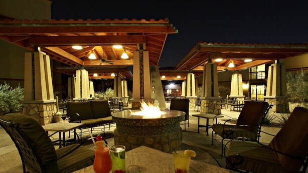 Un espacio de patio al aire libre con un brasero, asientos y bebidas.