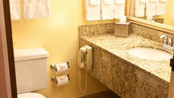 A bathroom with a toilet, sink, and mirror. There are towels hanging on the wall and a trash can.