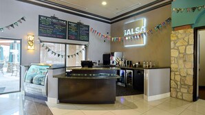 Zona de bar moderna con mostrador, vitrina de vidrio y menú en la pared que anuncia los especiales.