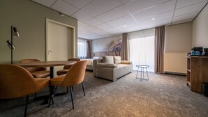 Une chambre d’hôtel moderne avec un coin repas, un canapé et une petite table.