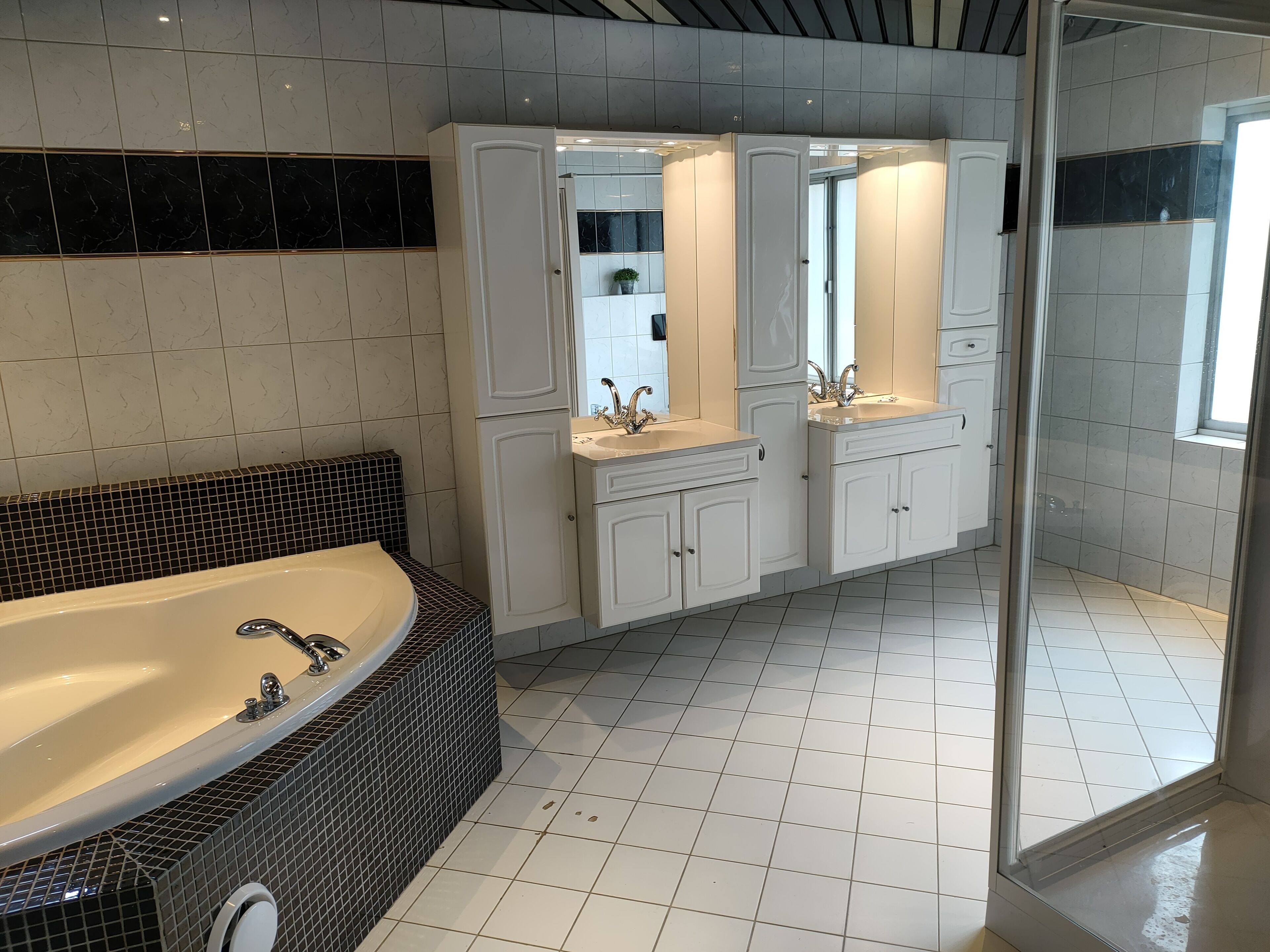 Un baño moderno con una bañera grande, dos lavamanos y una zona de ducha.