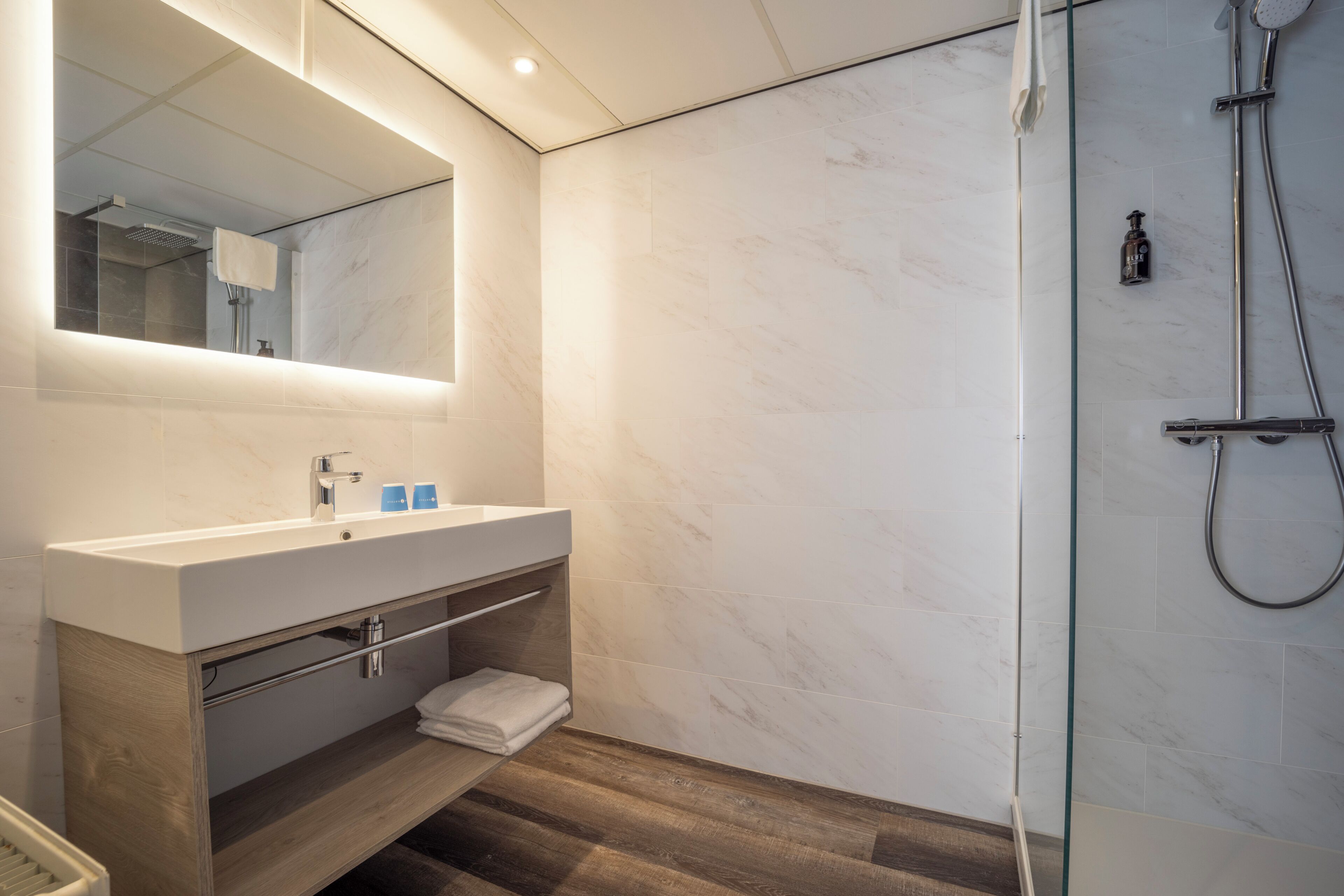 Une salle de bain moderne avec un grand miroir, un lavabo et une douche.