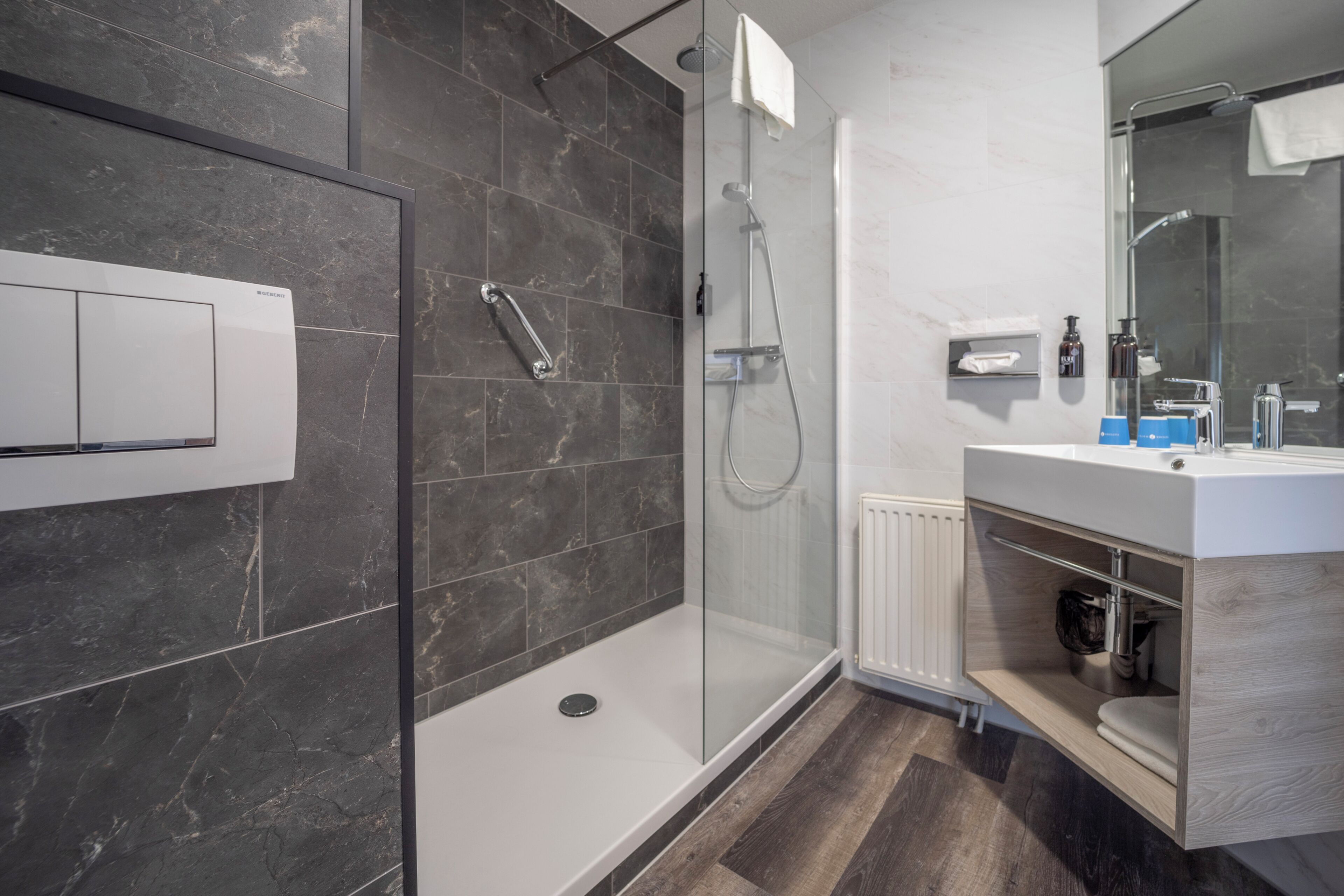 A modern bathroom with a glass-enclosed shower, a white sink, and a mirror.