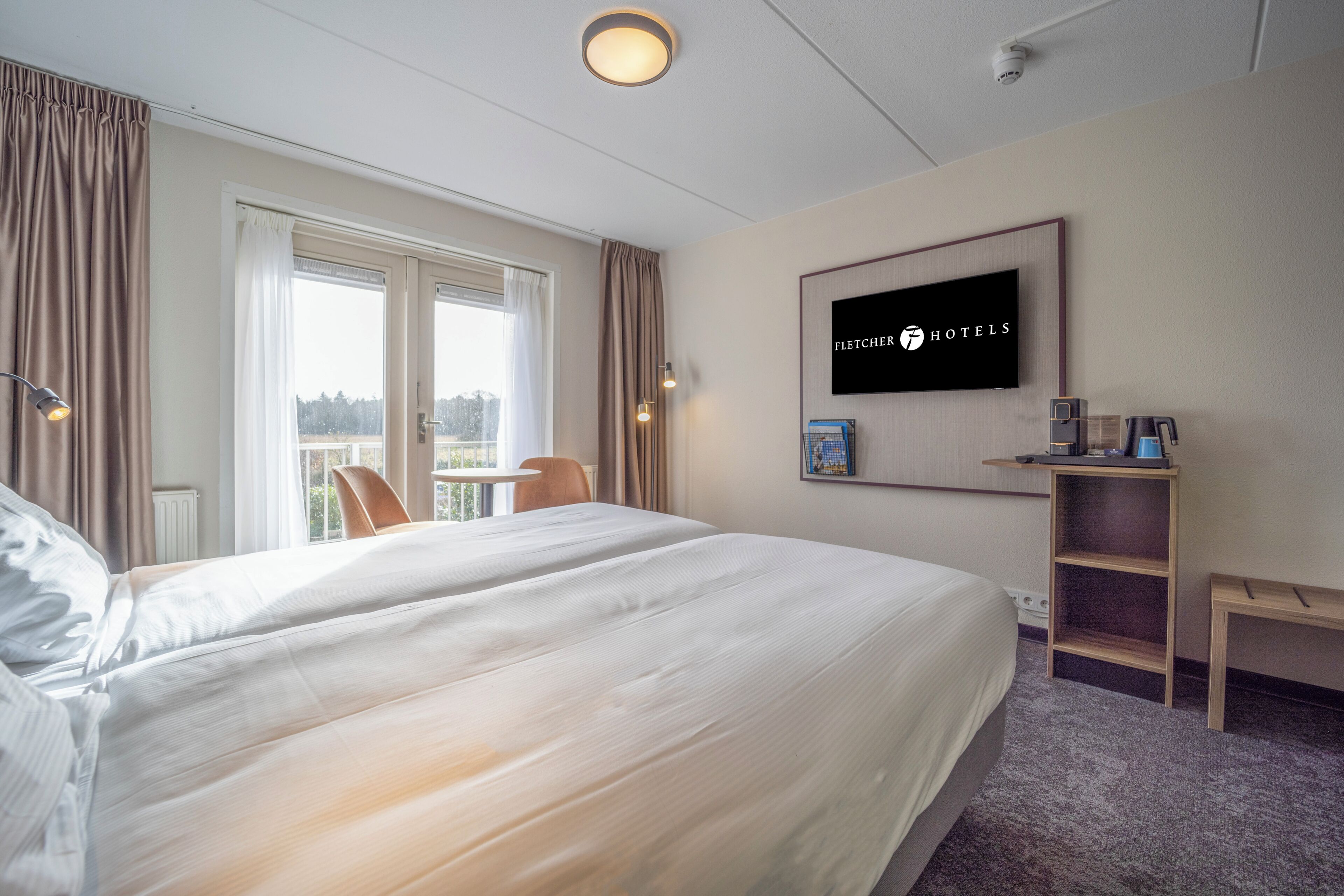 A hotel room with a large bed, a desk, a chair, a television, and a view of the outdoors.