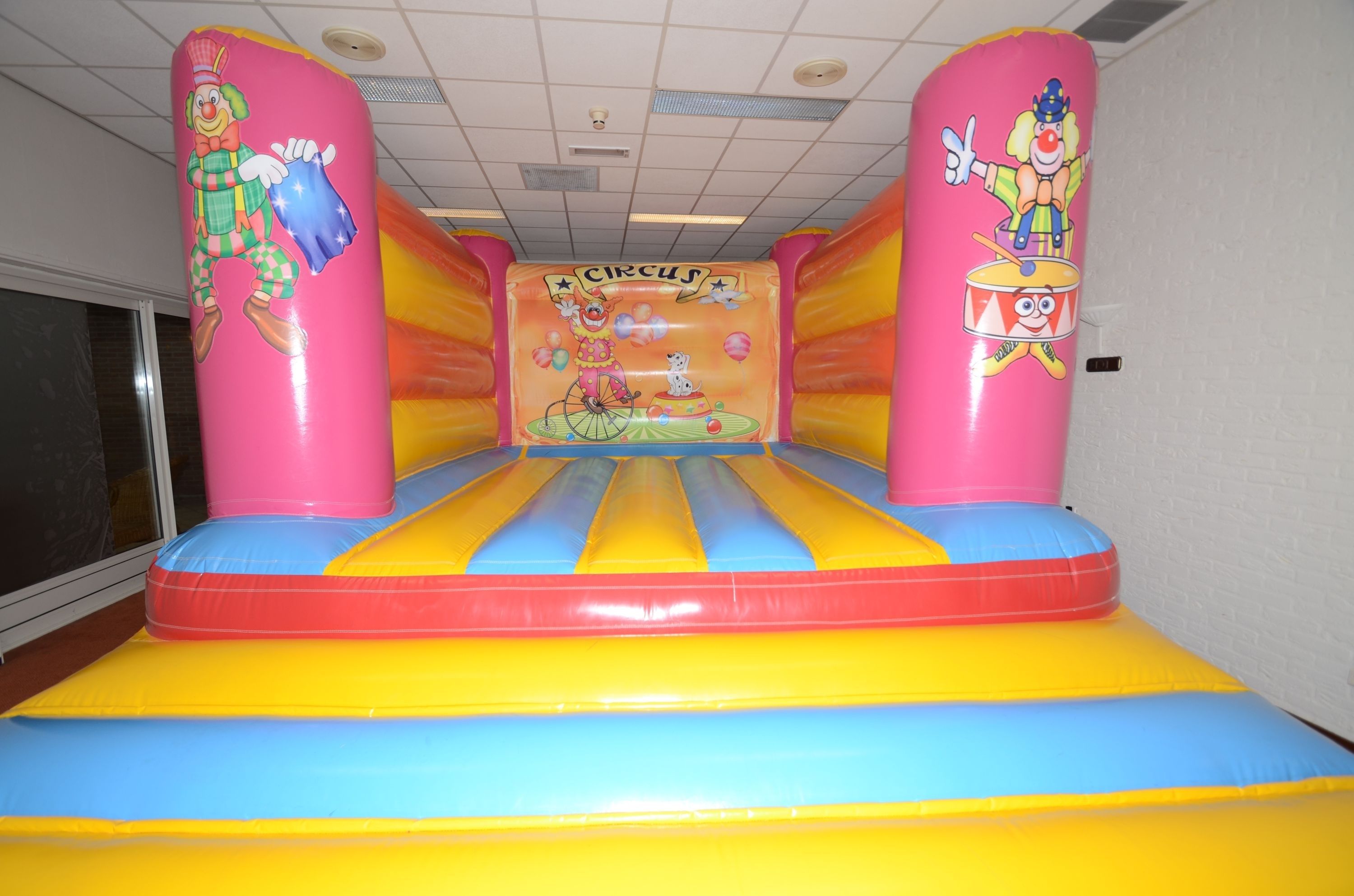 An indoor inflatable play area with cartoon clown designs and a circus theme.