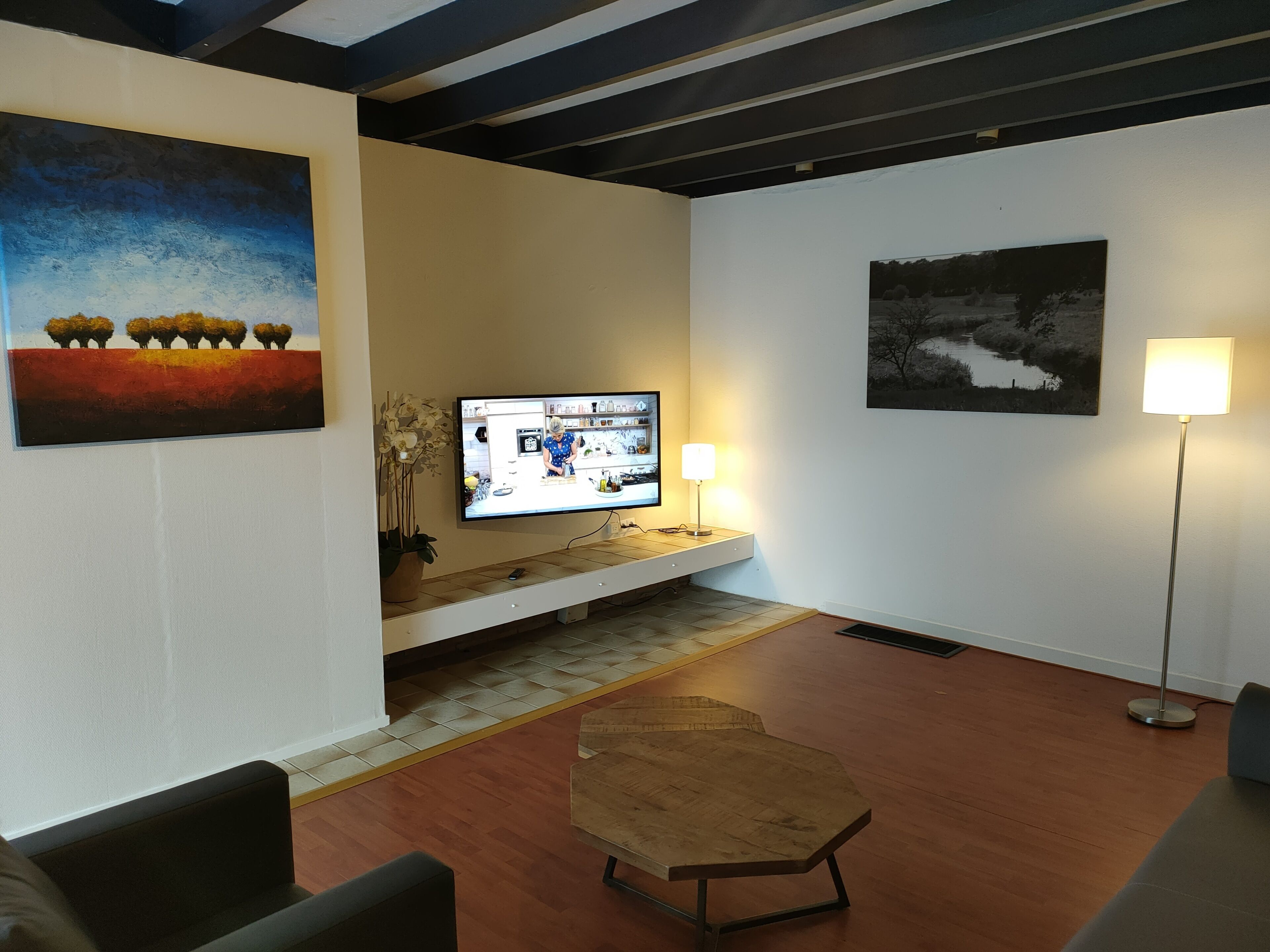 A modern living room with a flat-screen TV, a coffee table, and artwork on the walls.