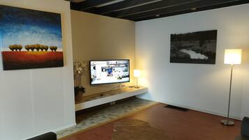 A modern living room with a flat-screen TV, a coffee table, and artwork on the walls.