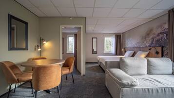 A hotel room with a dining area, a sofa, a bed, and a large window.