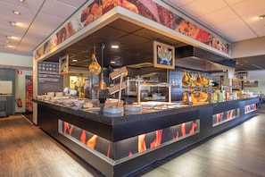A food counter with a variety of dishes and a fire feature. - Fletcher Hotel - Restaurant De Zeegser Duinen (Zeegse)