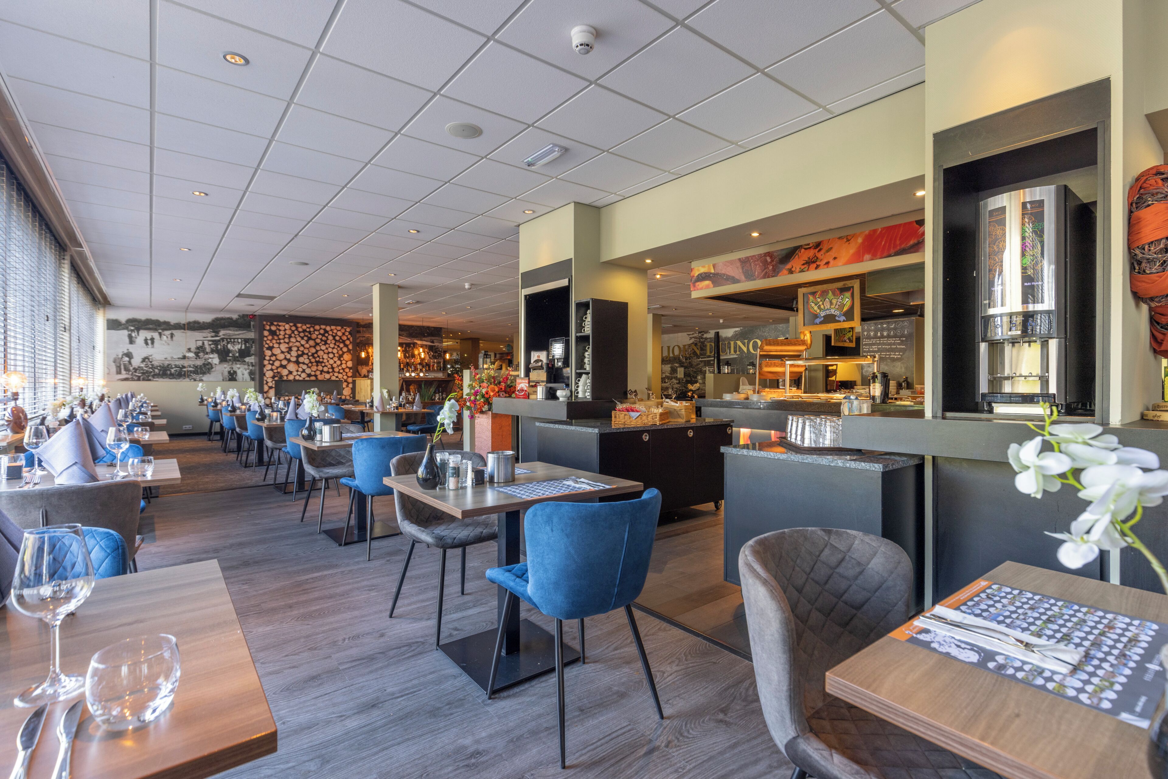 A restaurant with multiple tables and chairs, a bar area, and a mural on the wall.
