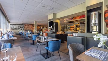 A restaurant with multiple tables and chairs, a bar area, and a mural on the wall.