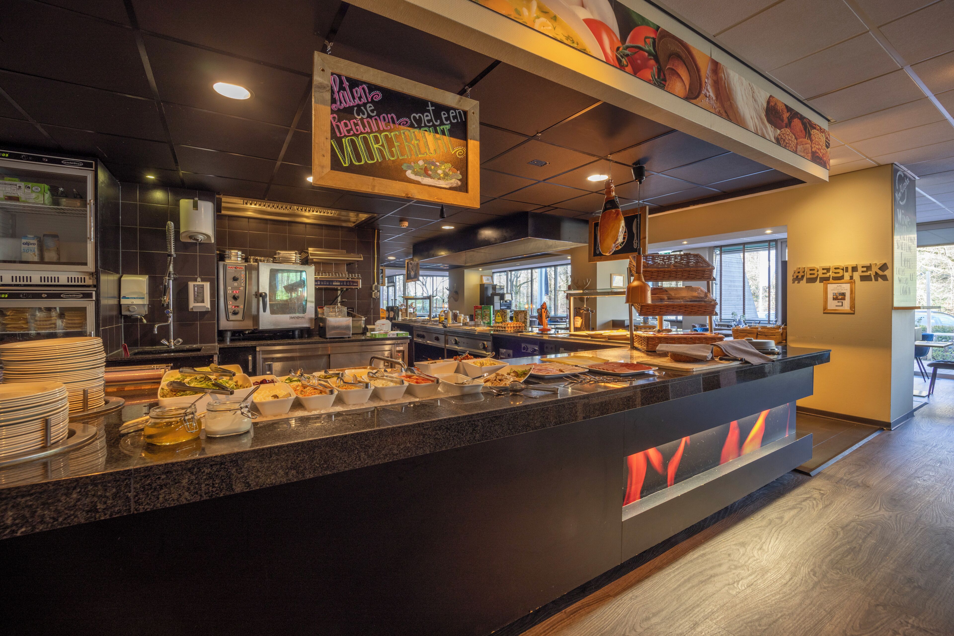 A buffet area with various food options, a coffee machine, and a sign with a message.