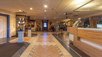 A hotel lobby with a reception desk, a seating area, and a display of items.