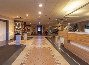 A hotel lobby with a reception desk, a seating area, and a display of items. - Fletcher Hotel - Restaurant De Zeegser Duinen (Zeegse)
