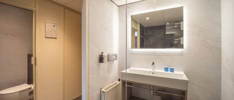 Un baño moderno con inodoro, lavabo y espejo.