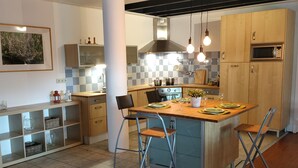 Une cuisine moderne dotée d’un îlot central, de meubles en bois et d’un pare-feu en carreaux.