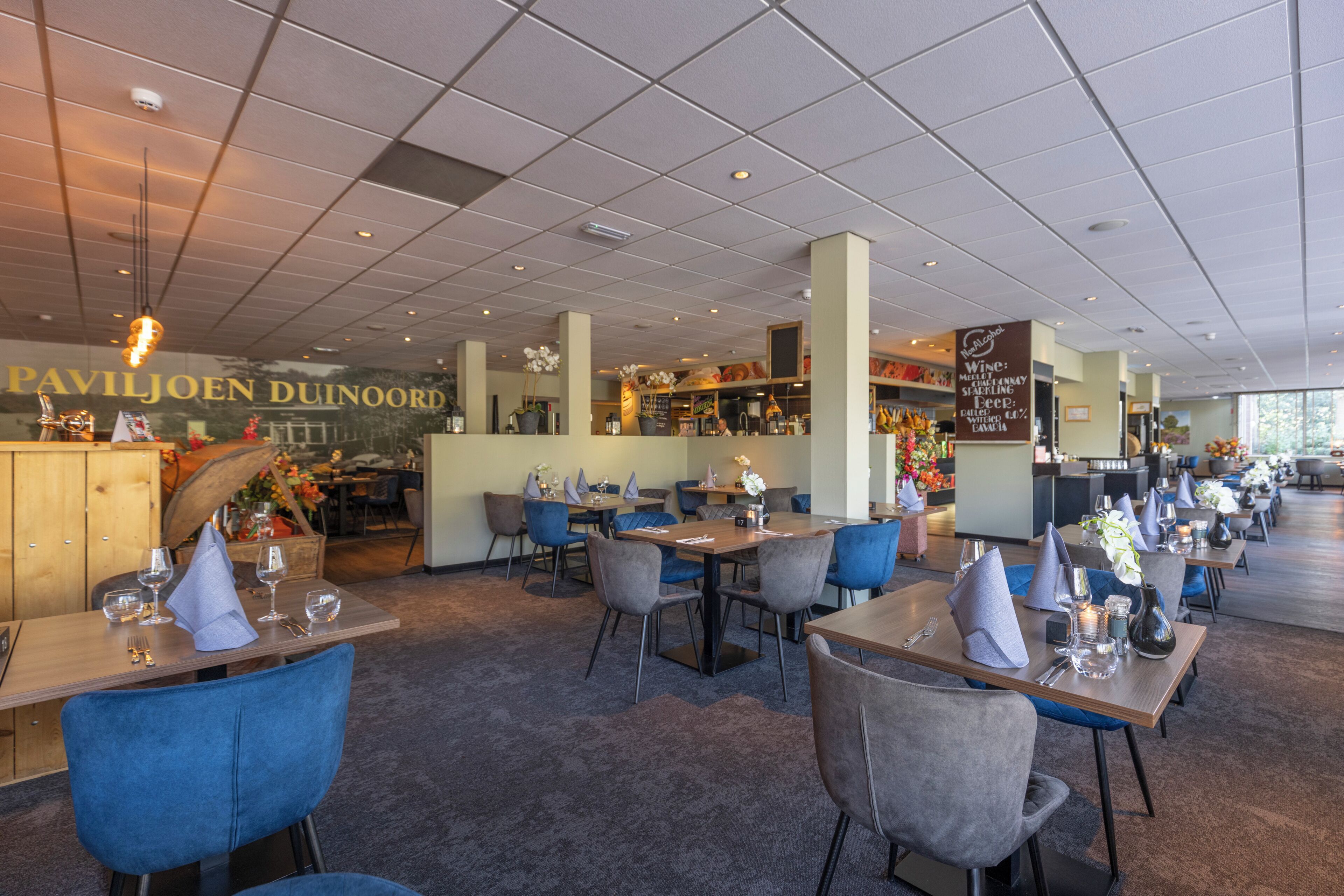 A restaurant with multiple tables and chairs, a bar area, and a visible menu board.
