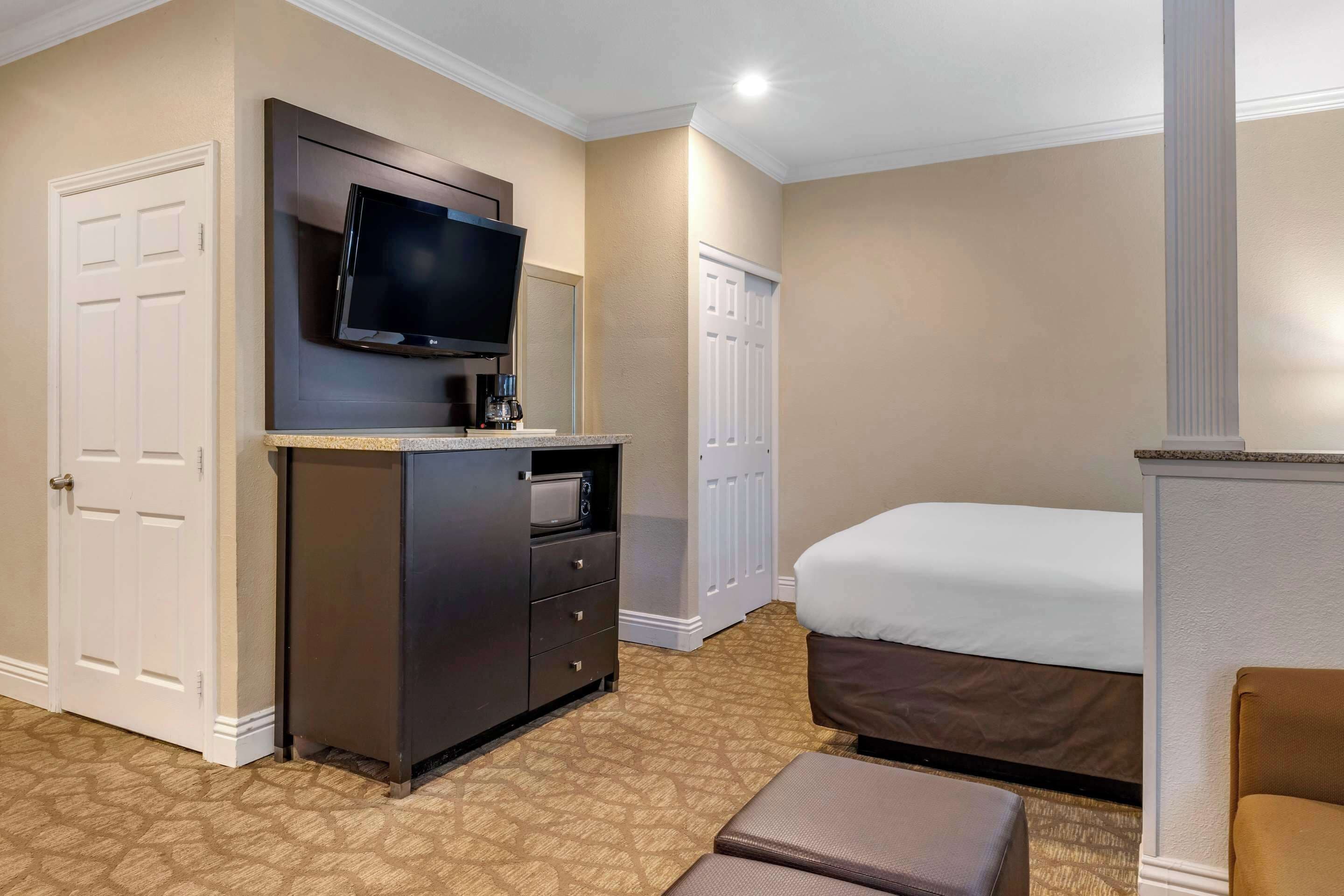 Une chambre d’hôtel équipée d’un lit, d’un téléviseur fixé à un meuble, d’un four à micro-ondes et d’une machine à café.