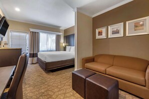 A hotel room with a bed, a sofa, a desk, and a television. - Comfort Inn & Suites Huntington Beach (Huntington Beach)