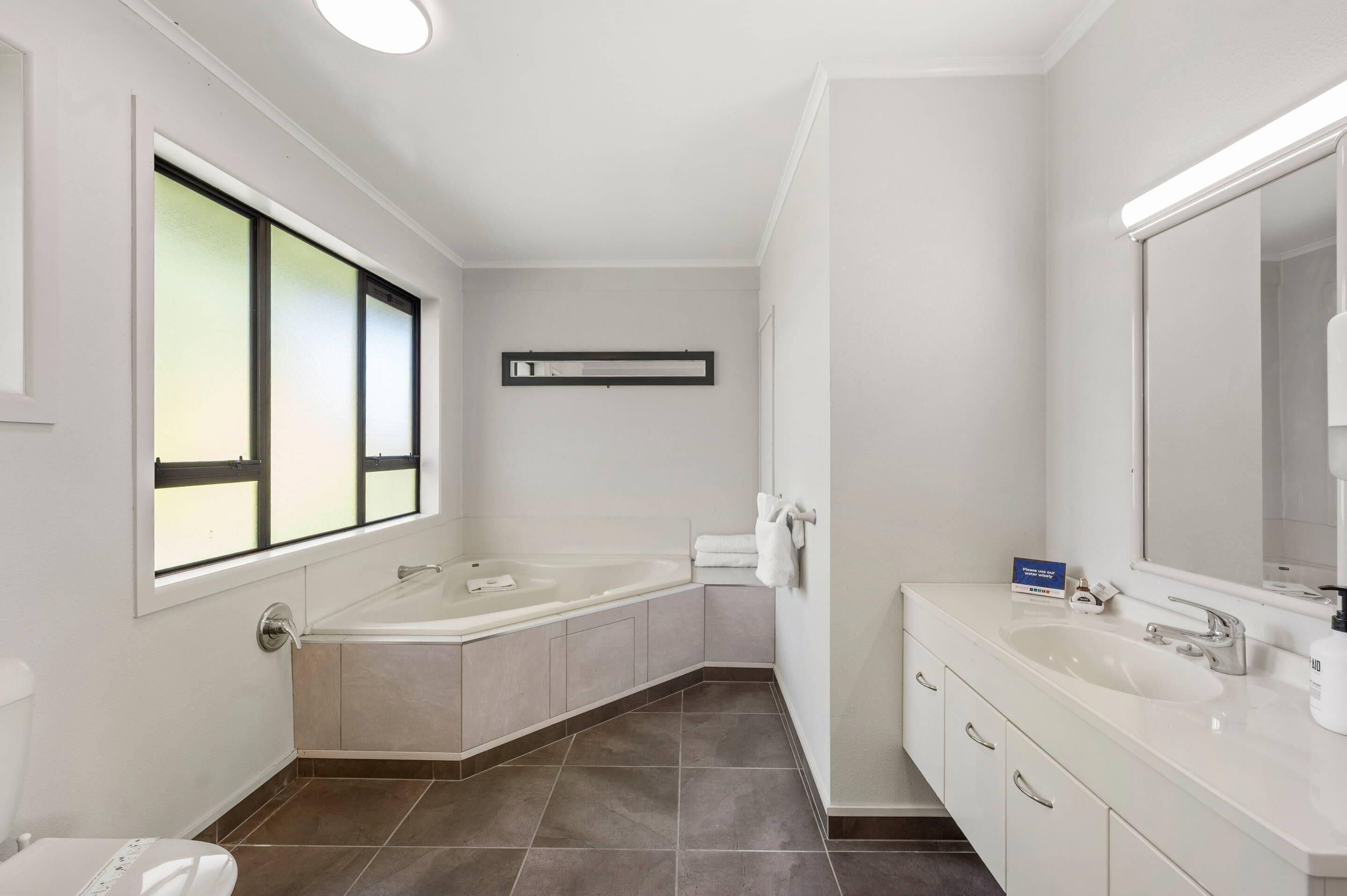 A modern bathroom with a large bathtub, a vanity with a sink, and a mirror.