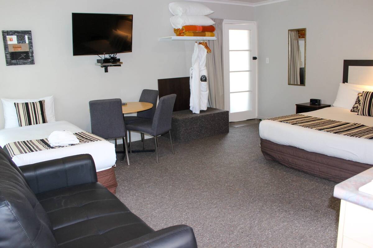 Een hotelkamer met een bed, een bank, een bureau, een stoel, een televisie en een spiegel.