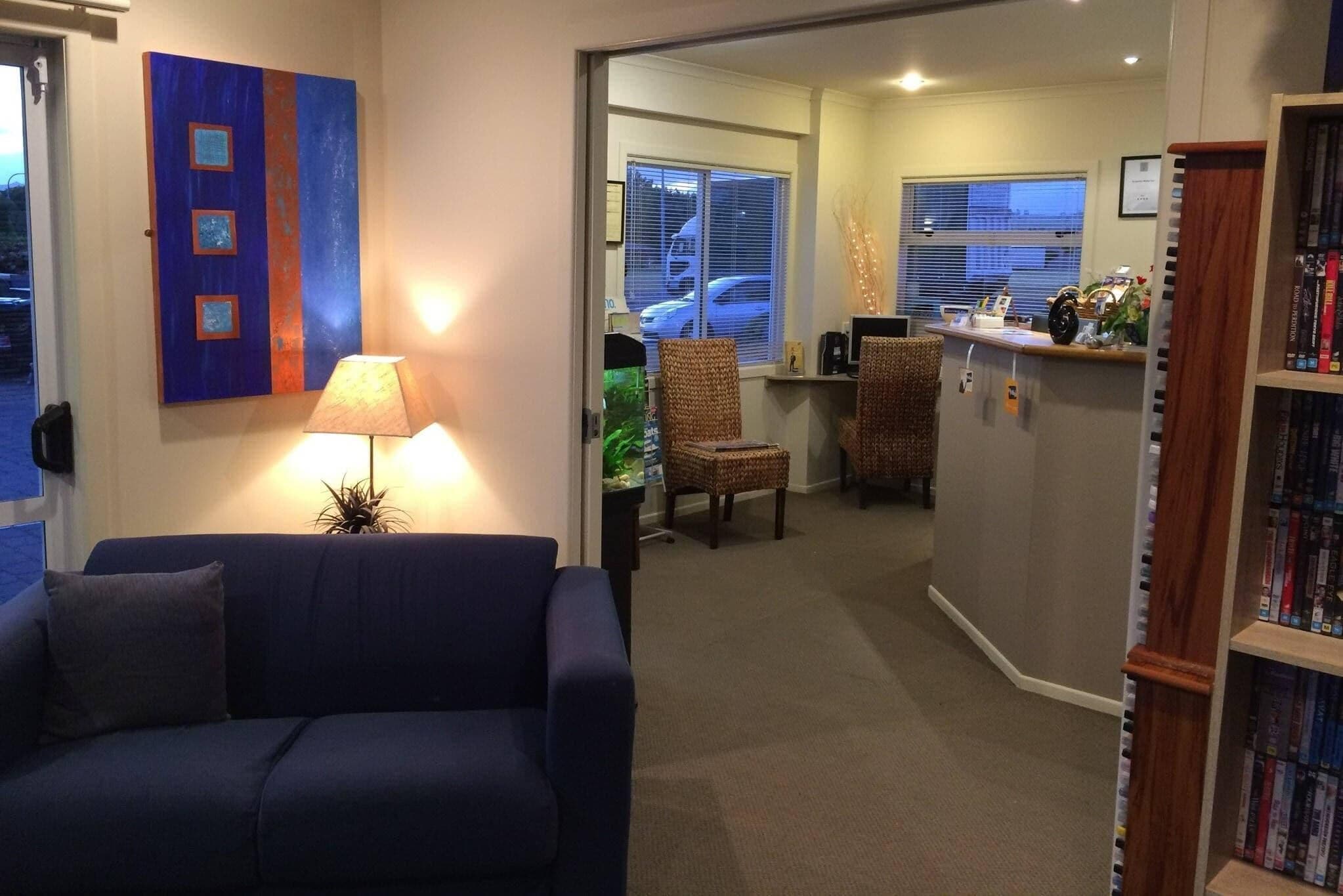 A living room with a blue sofa, a lamp, and a bookshelf.