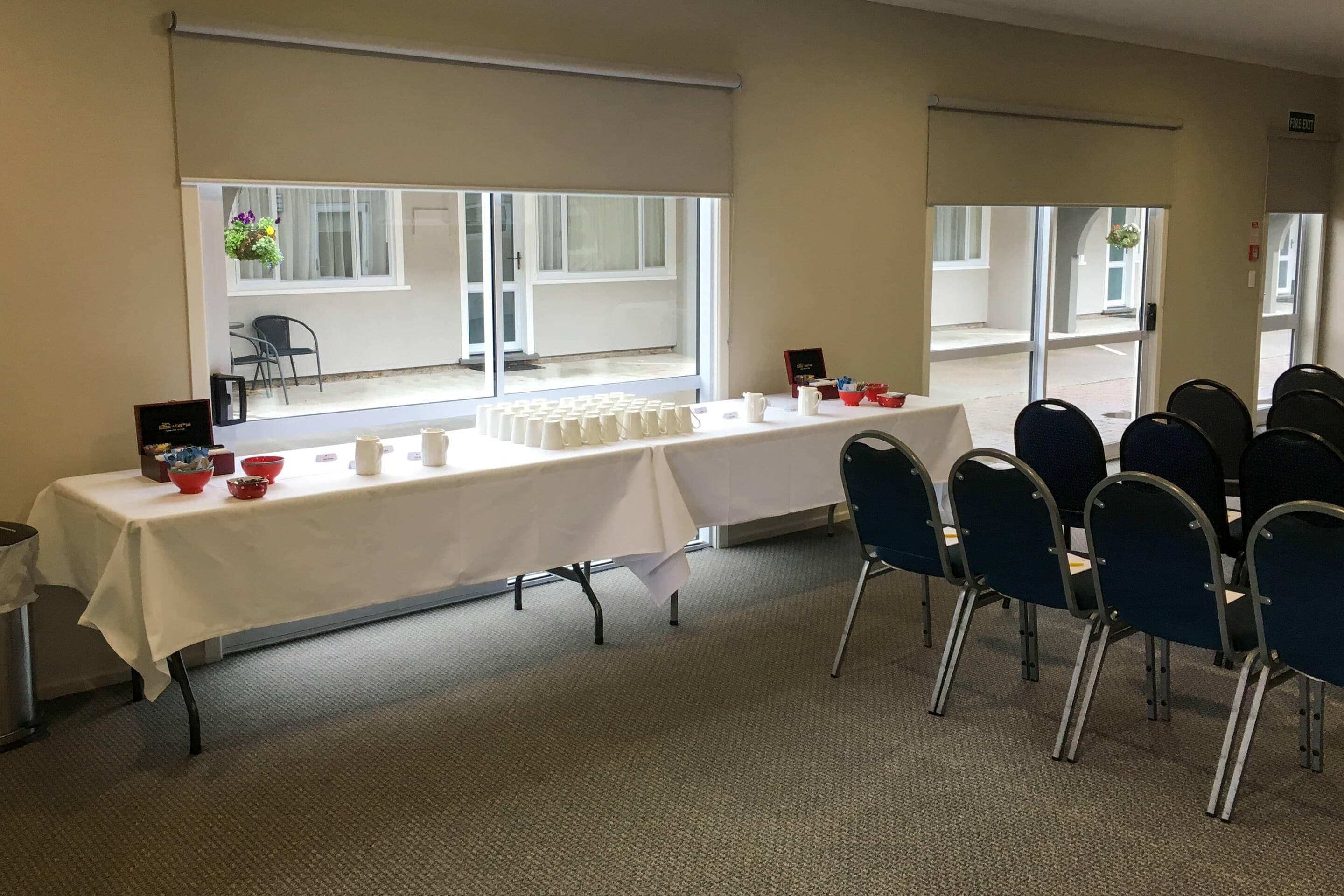 Une salle de conférence avec une longue table, des chaises et une fenêtre donnant sur l’extérieur.