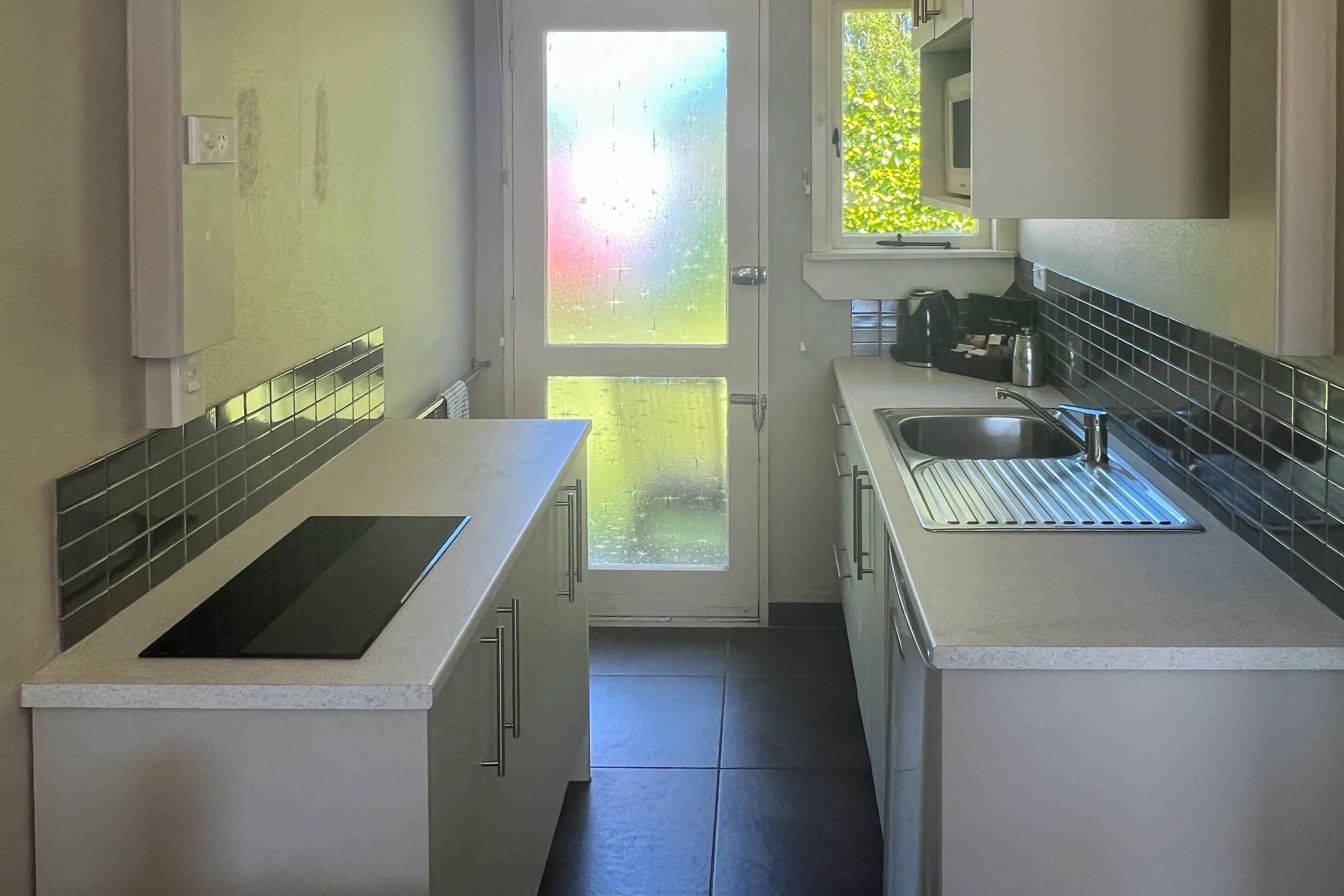 Una cocina compacta con una isla central, un ventanal con vistas y un horno empotrado.