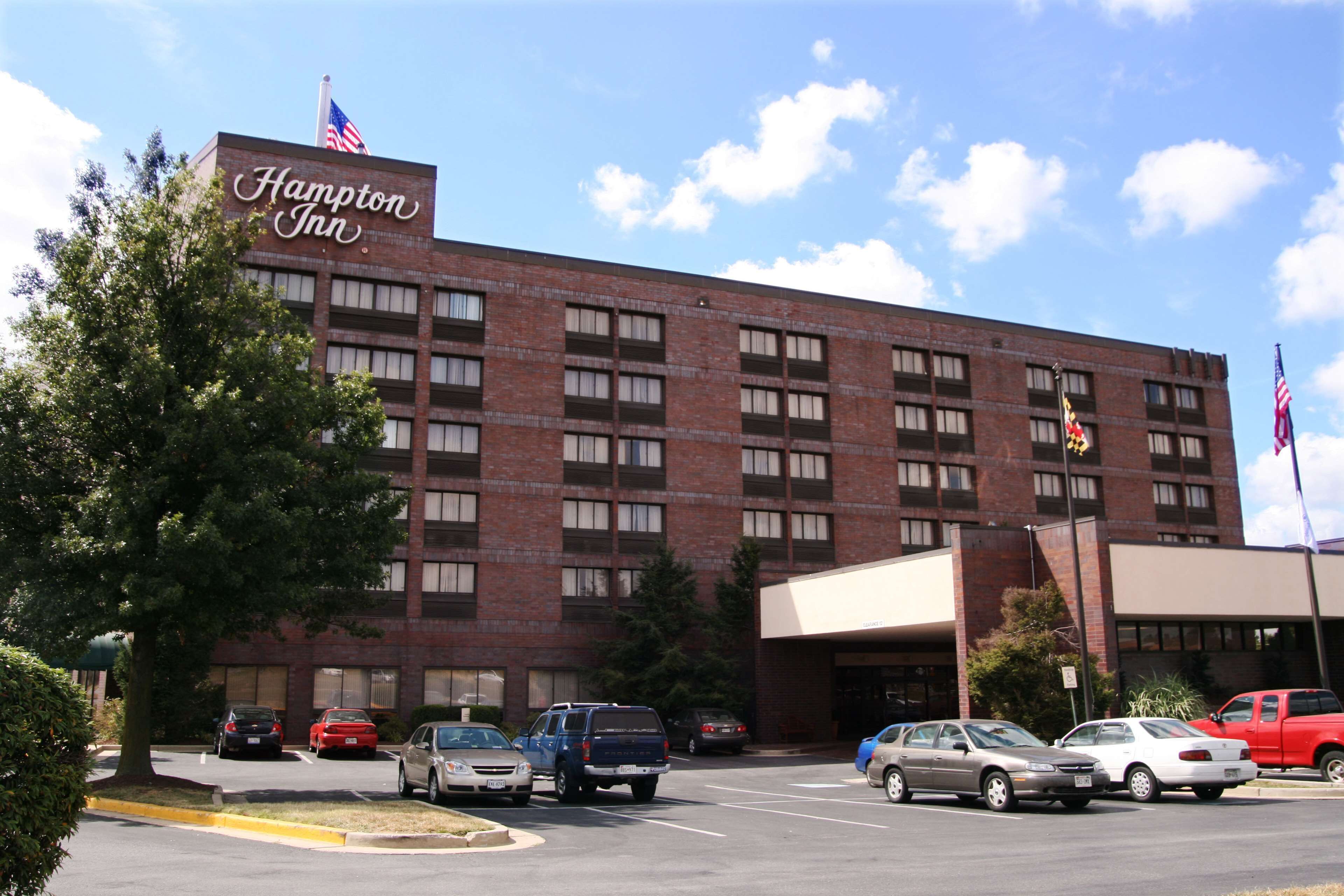 Un hôtel Hampton Inn avec une façade en briques, de nombreuses fenêtres et des drapeaux.