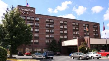 Un hôtel Hampton Inn avec une façade en briques, de nombreuses fenêtres et des drapeaux.
