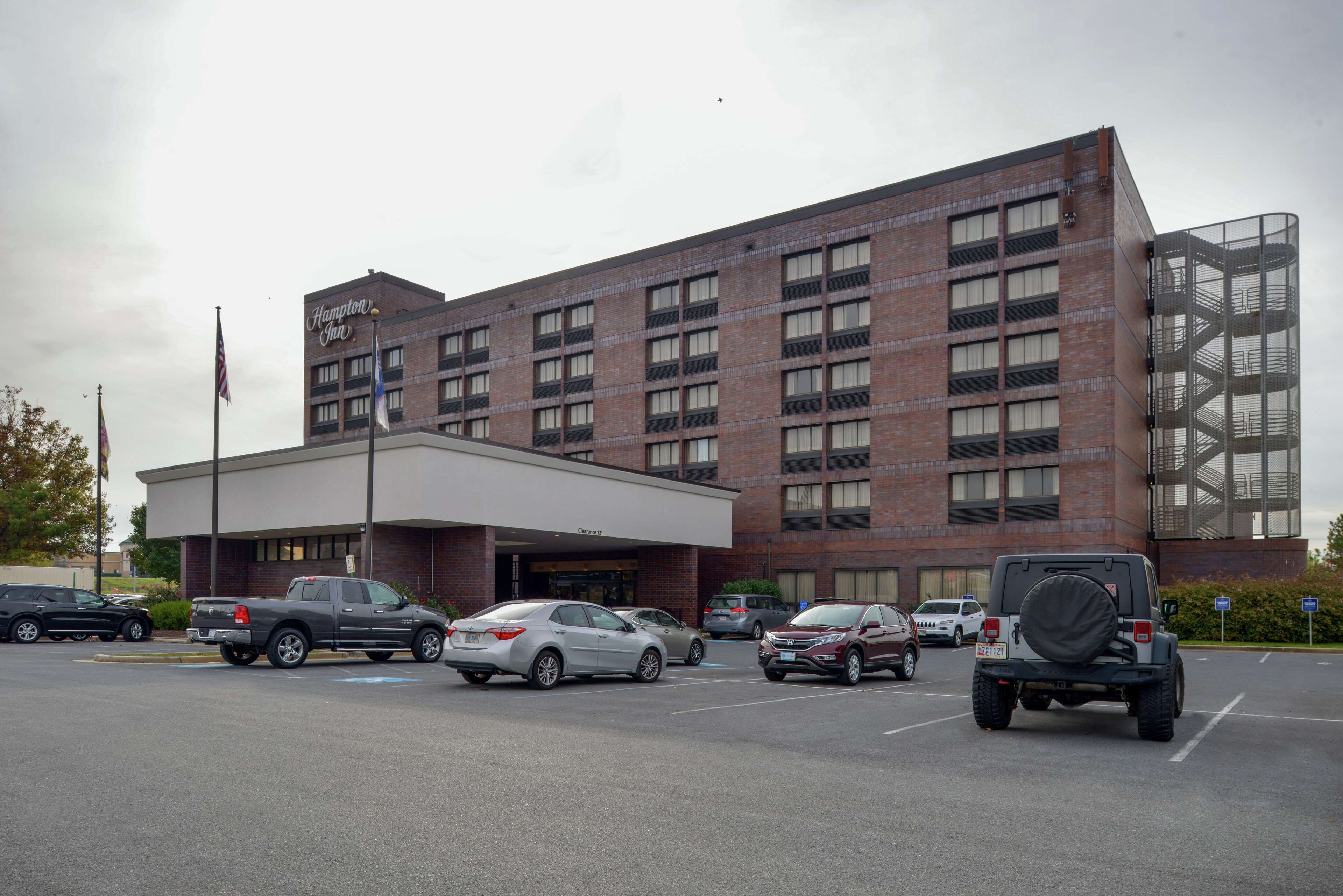 A hotel with a brick facade, multiple parking spaces, and a flag.