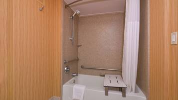 Een badkamer met een bad, een douche, een handgreep en een handdoekhouder.