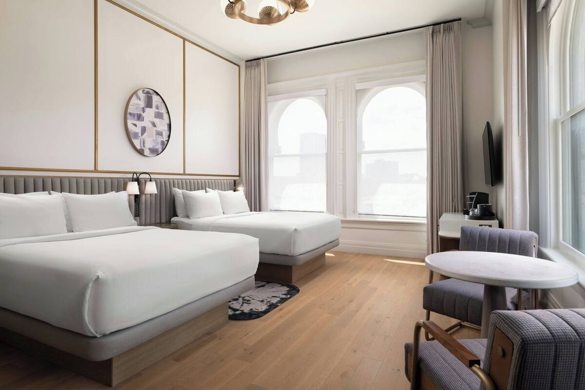 Ein Hotelzimmer mit zwei Betten, einem kleinen Tisch und einem Fernseher.