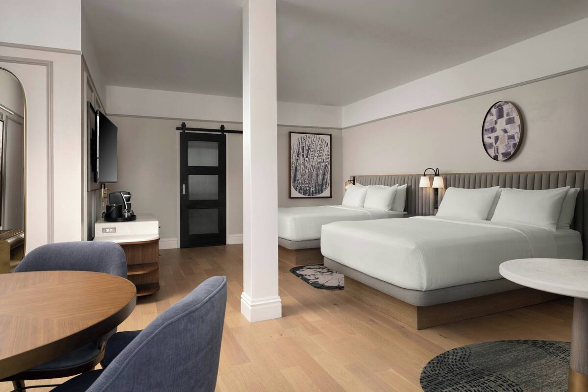 Ein modernes Hotelzimmer mit einem Bett, zwei Nachttischen, einem Schreibtisch und einem Sessel.