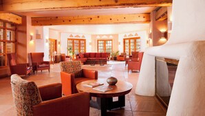 A spacious lobby with wooden beams, a fireplace, and multiple seating areas.
