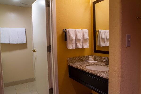 A bathroom with a white sink, a mirror, and two white towels hanging on the wall.