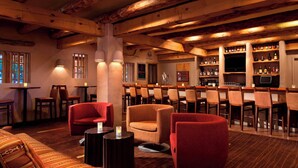 A bar area with wooden beams, bar stools, and a variety of liquor bottles.