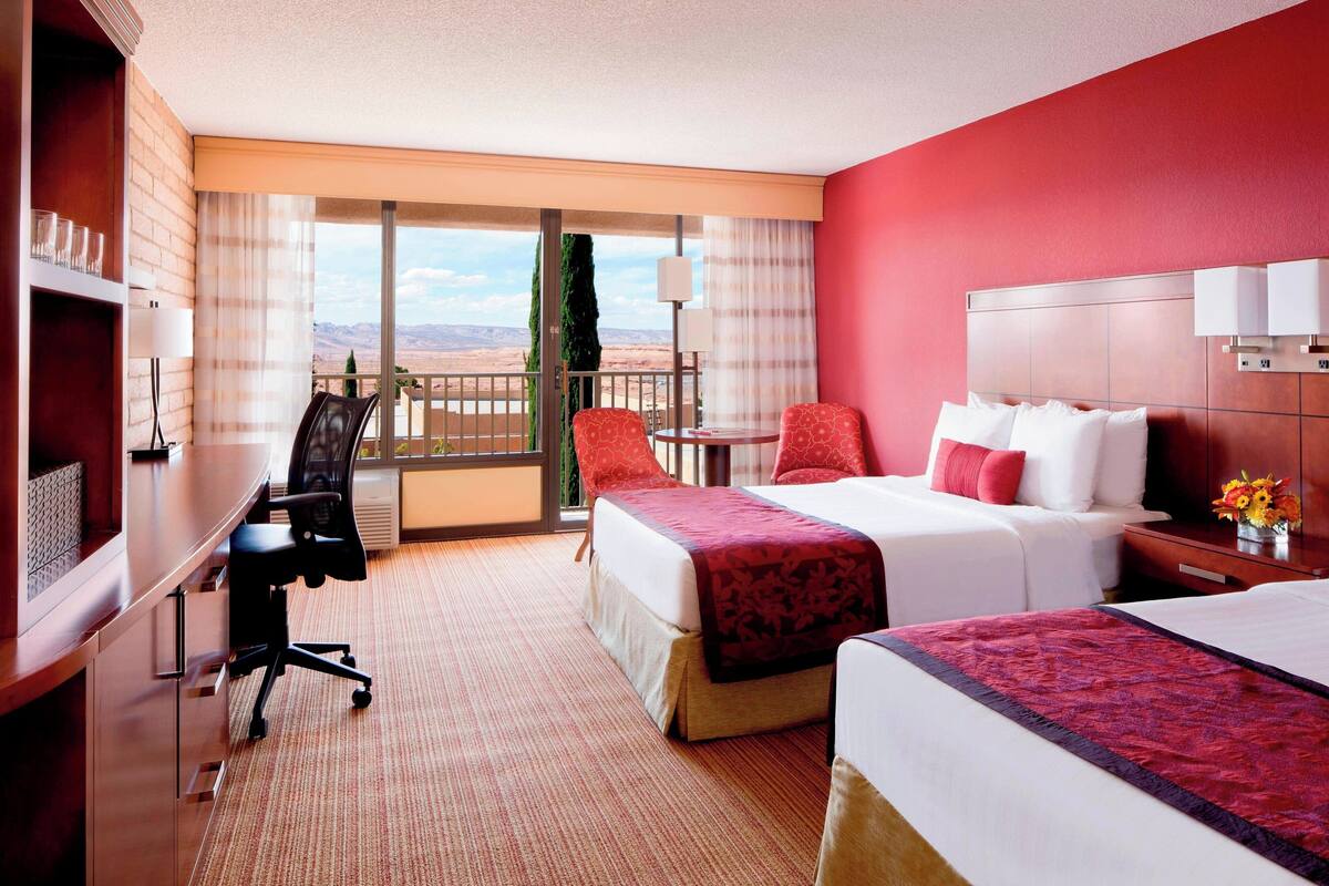 Une chambre d’hôtel avec un grand lit, un bureau, une chaise et une vue sur le désert.